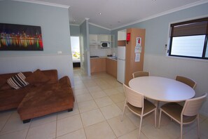 Un espacio habitable pequeño con sofá, mesa de comedor y kitchenette.