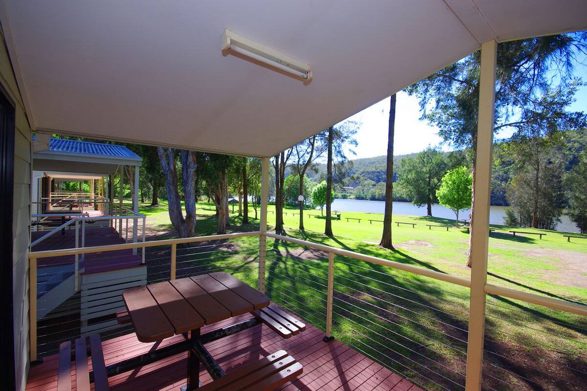 A covered outdoor area with a picnic table and benches, overlooking a lake and trees.