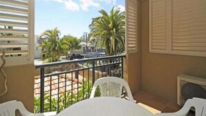 Un balcón con vista a palmeras y una calle.