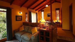 A cozy living room with a sofa, a lamp, and a small table. - Wombat Hills Cottages (Barwite)