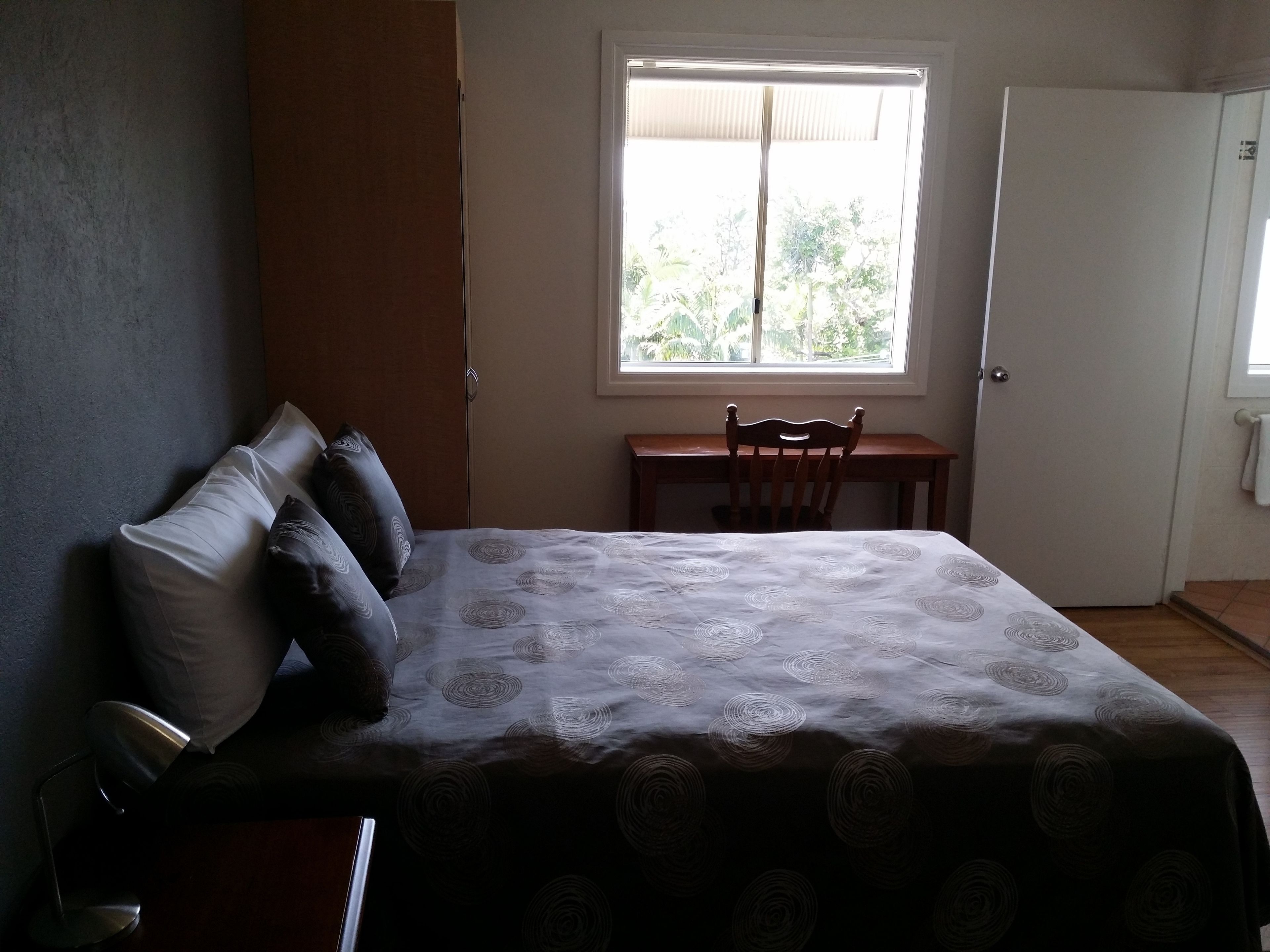 Ein Schlafzimmer mit einem Bett, einem Schreibtisch und einem Fenster.