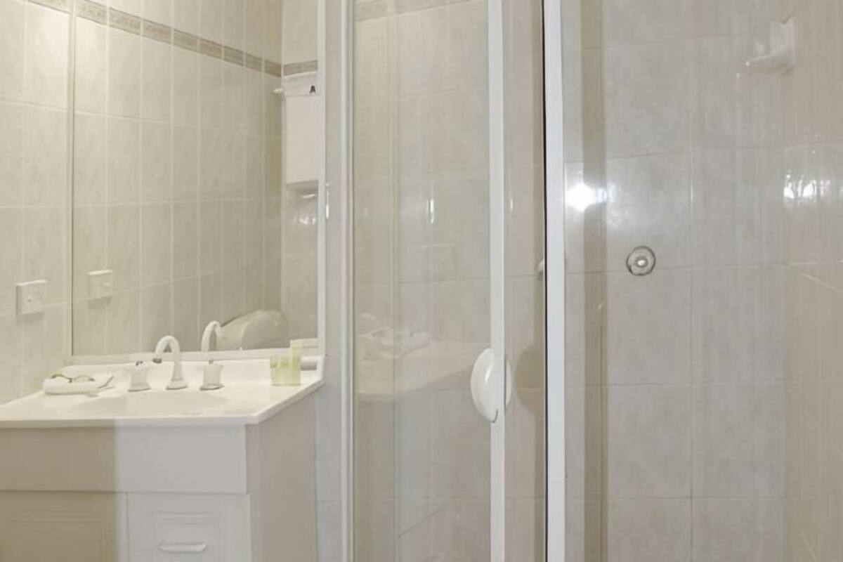 Une salle de bain avec une douche à parois de verre, un lavabo blanc et un miroir.
