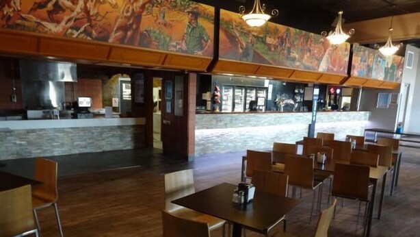 A restaurant with wooden flooring, multiple tables and chairs, and a mural on the wall. - Jolly Collier Hotel Motel (Dysart)