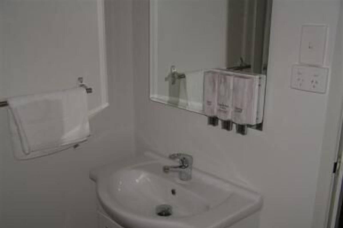 Une salle de bain avec un lavabo blanc, un miroir et une serviette accrochée au mur.