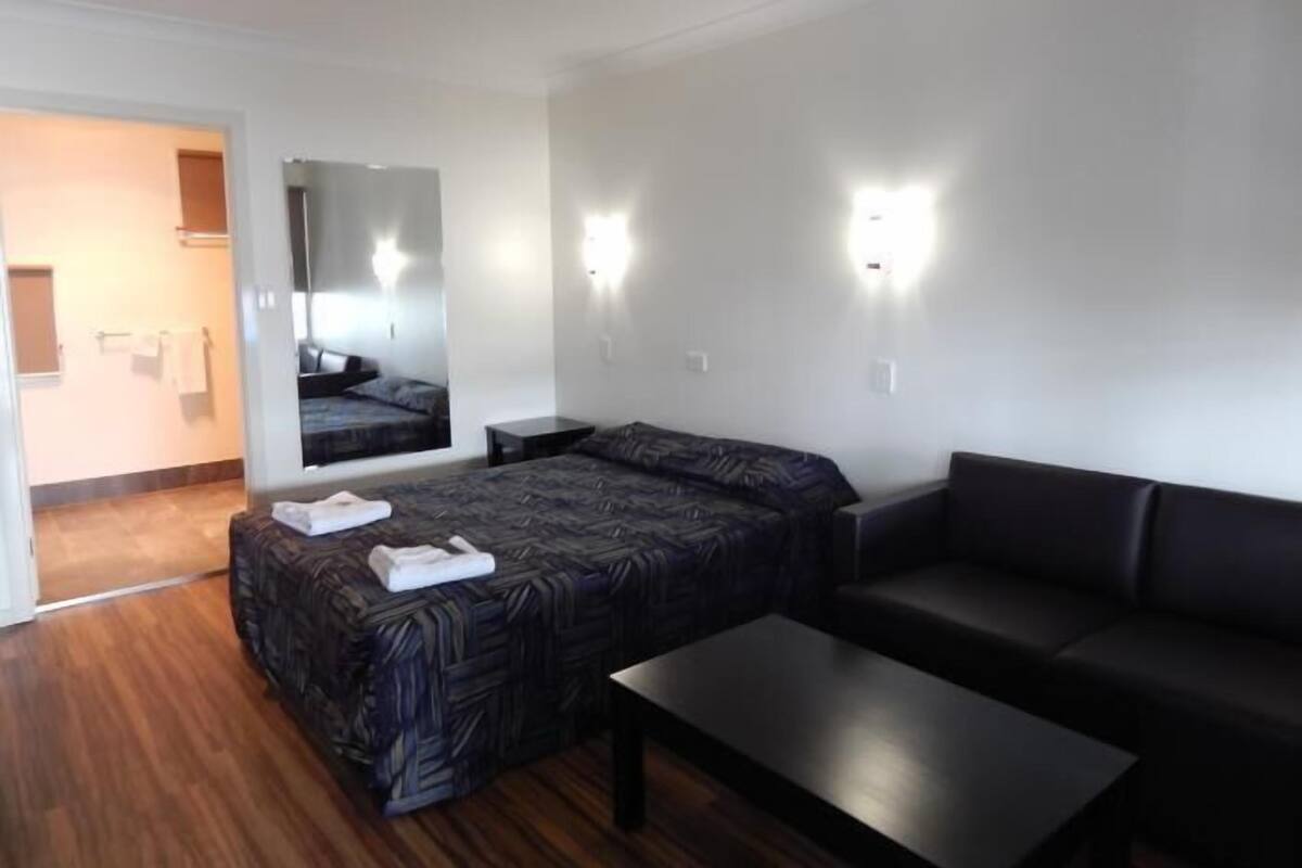 Une chambre d’hôtel moderne, équipée d’un lit, d’un canapé, d’une petite table et d’un miroir.