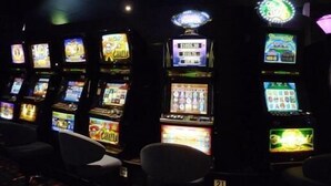A row of slot machines in a dimly lit room with chairs in front. - Jolly Collier Hotel Motel (Dysart)