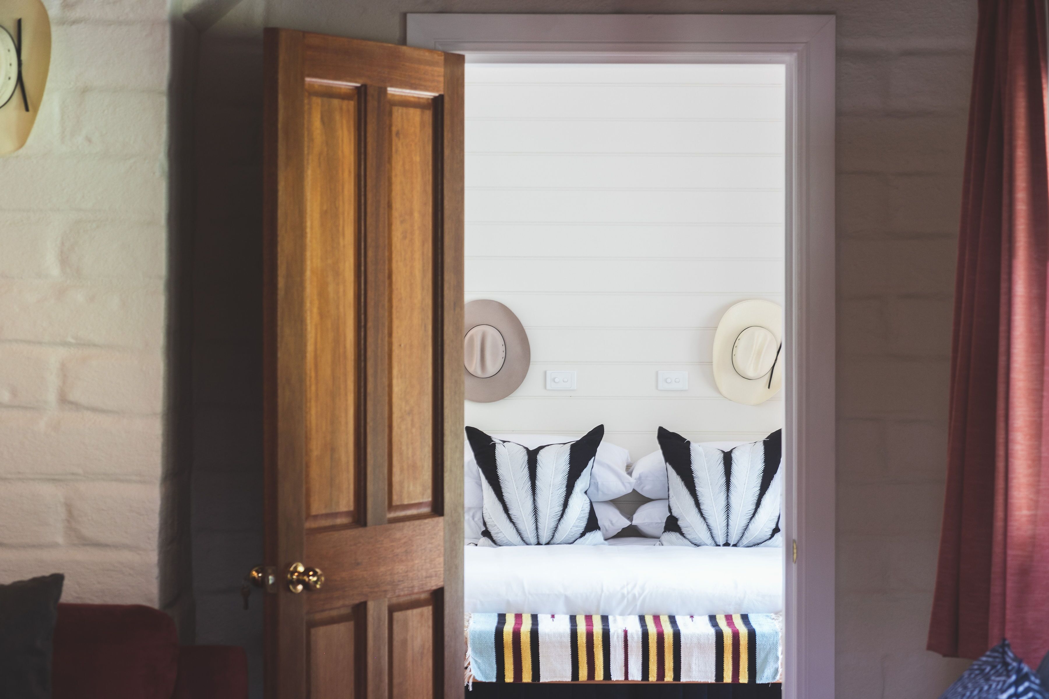 A bedroom with a wooden wardrobe, a bed with striped bedding, and a white headboard.