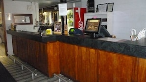 Un espace d’accueil avec un comptoir en bois, un réfrigérateur Coca-Cola, un écran numérique et un certificat encadré accroché au mur.