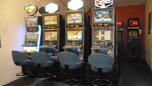 Un espace bar équipé de quatre machines de jeux et de quatre tabourets de bar.
