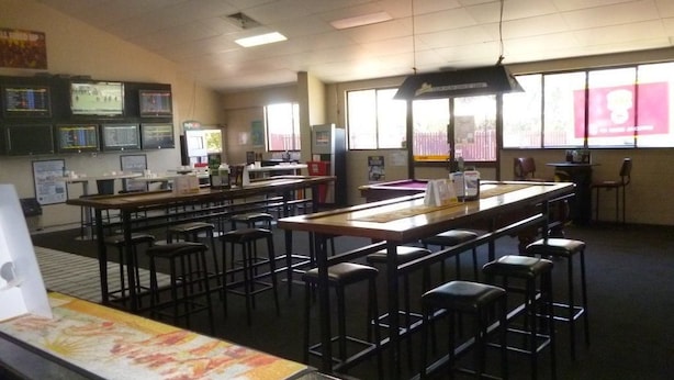 Une salle de classe équipée de plusieurs tables et chaises, d’une grande fenêtre et de plusieurs écrans fixés au mur.