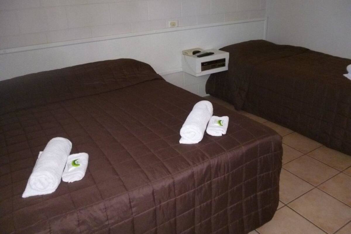 Ett hotellrum med två sängar, var och en med ett brunt överkast och prydligt hopvikta vita handdukar.