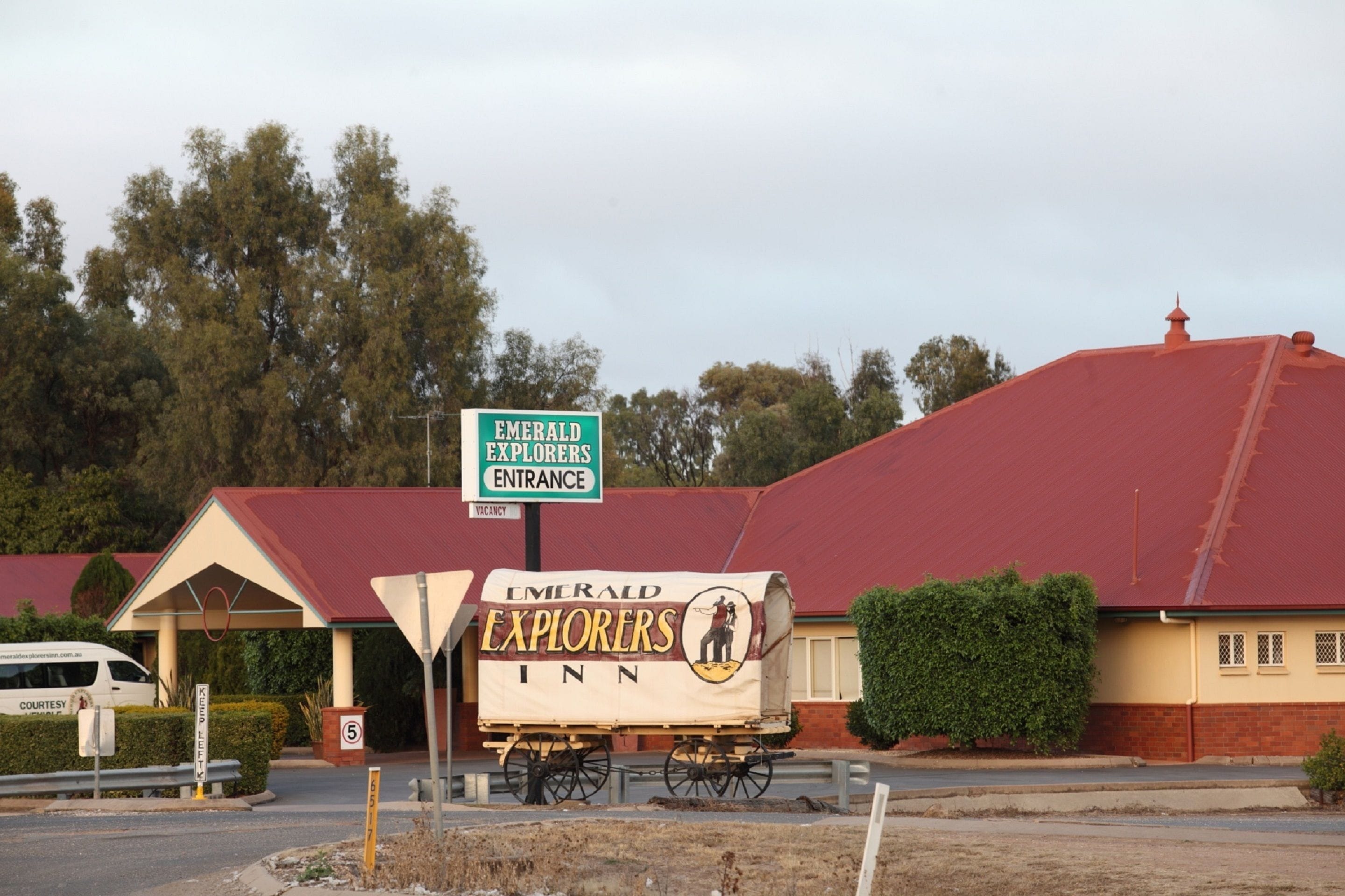 A building with a sign reading "Emerald Explorers Inn" and a covered wagon with the same name.