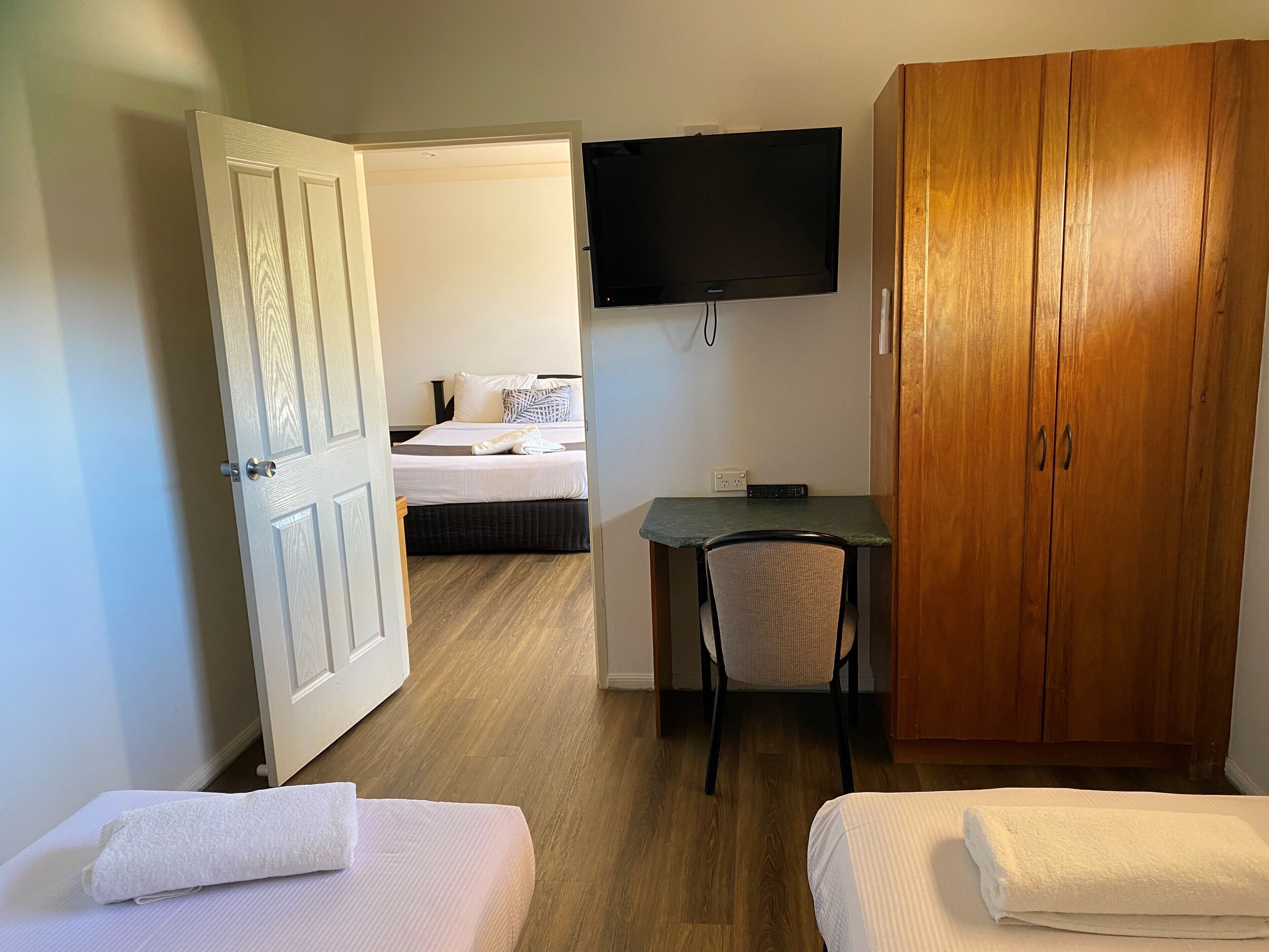 A hotel room with a bed, a desk, a television, and a wardrobe.