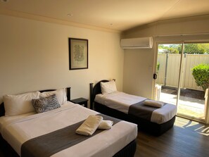A hotel room with two beds, a framed picture on the wall, and an air conditioning unit.