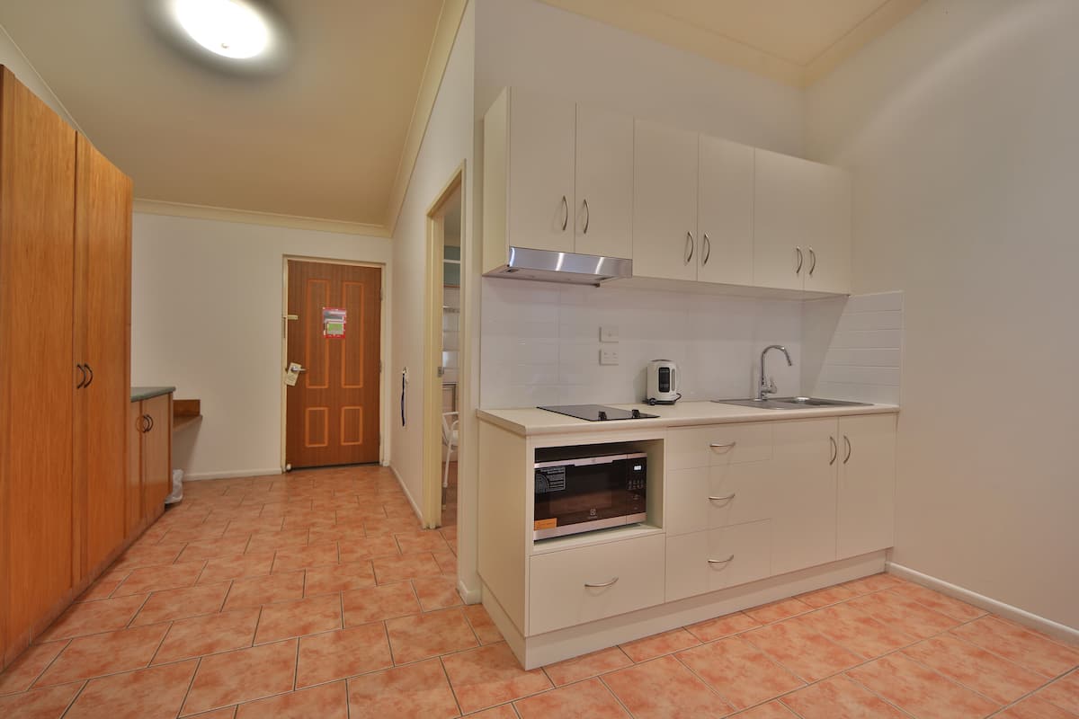 A compact kitchen with white cabinets, a built-in microwave, and a sink.