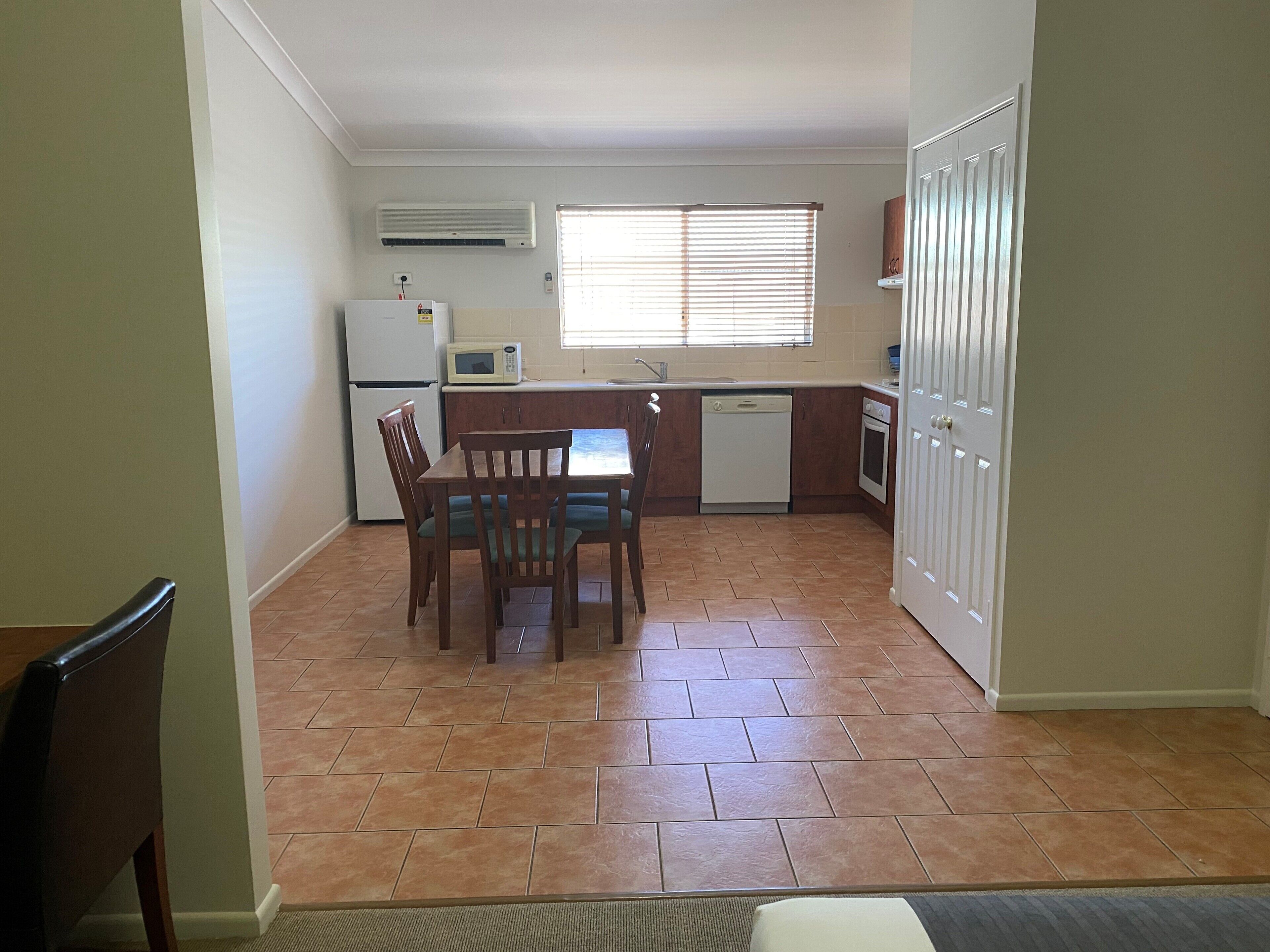 A compact kitchen with a dining area, a refrigerator, a microwave, a dishwasher, and a stove.