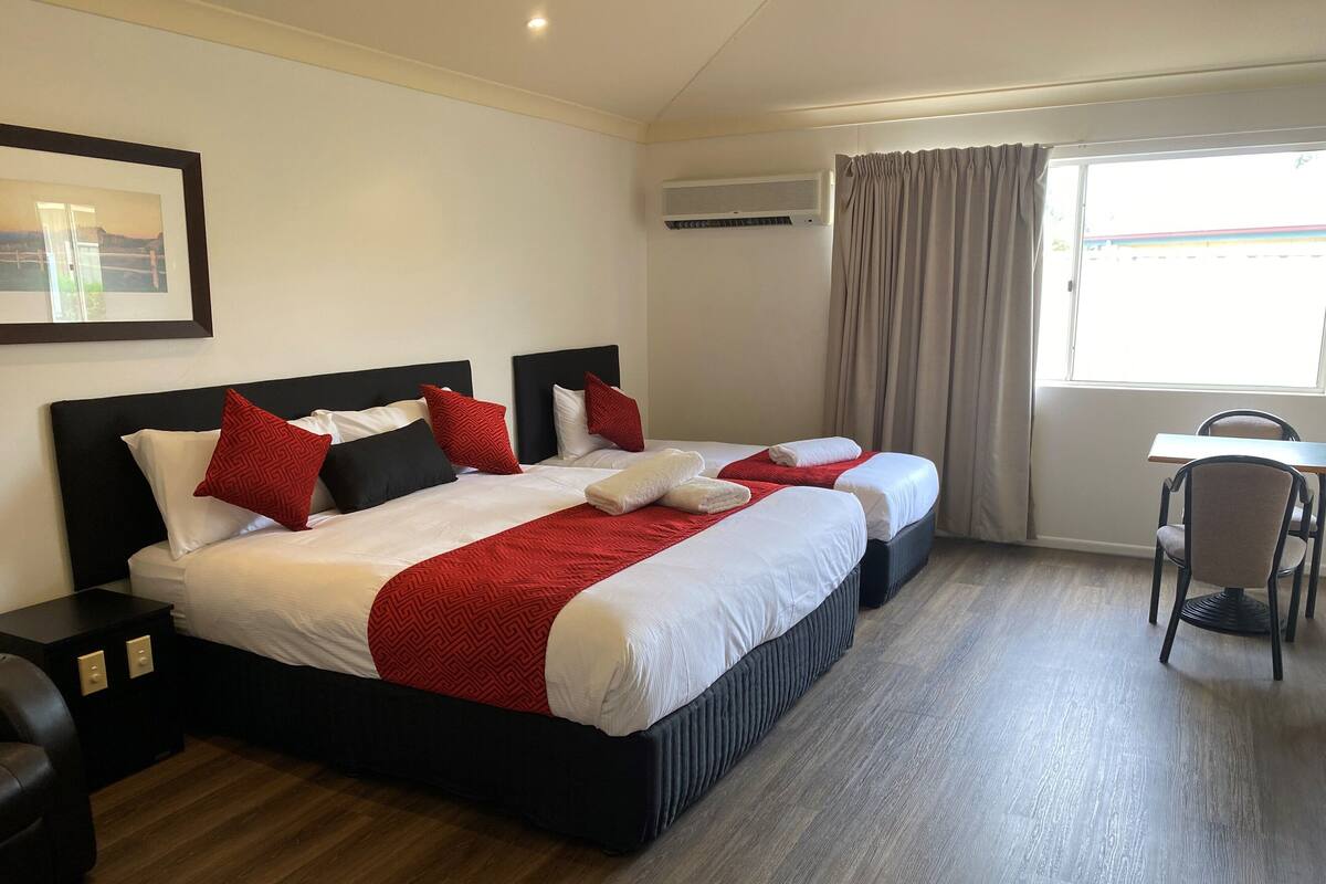 A hotel room with a large bed, two bedside tables, a chair, and a desk.