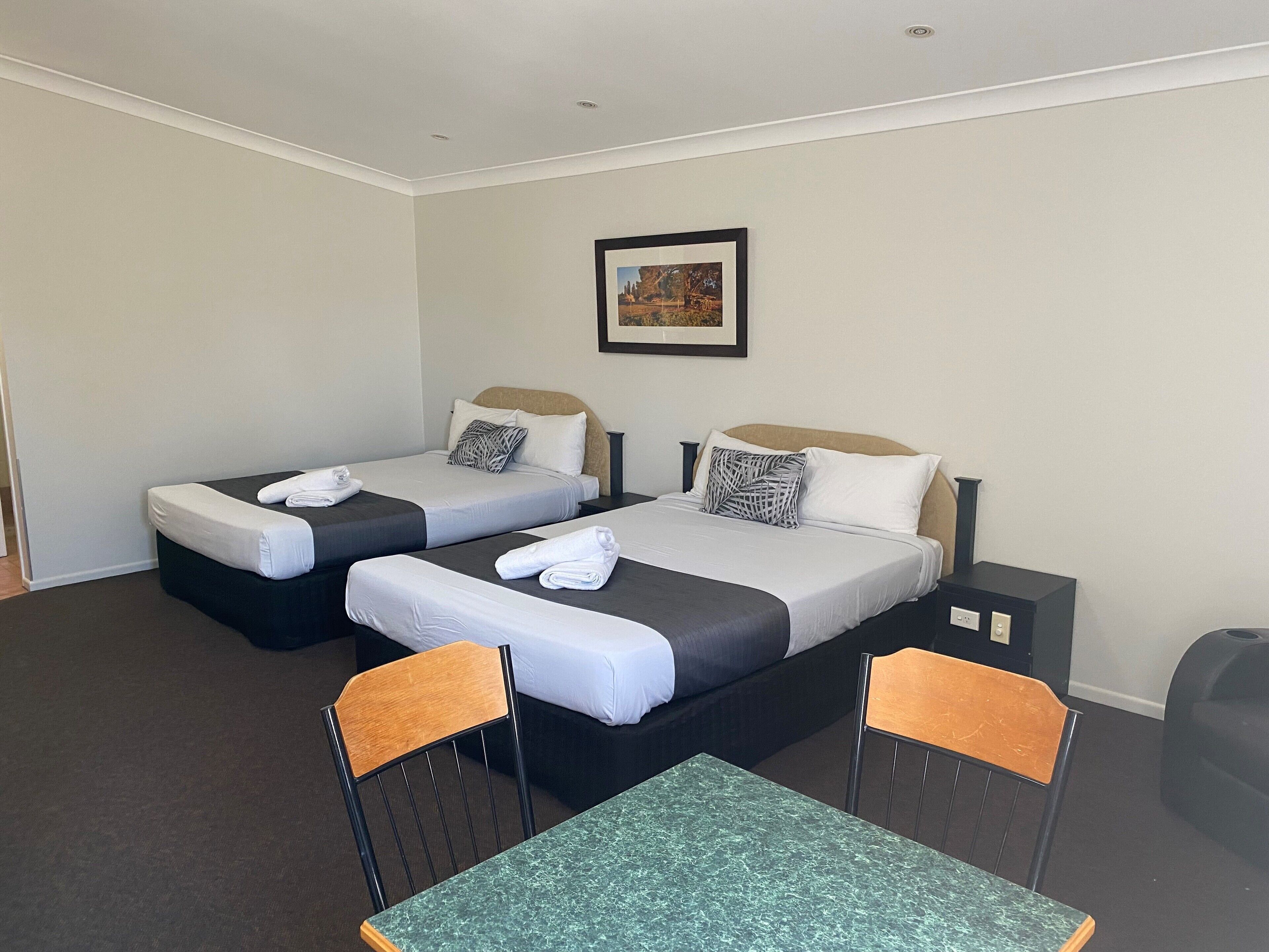 Una habitación de hotel con dos camas, una mesa y dos sillas.