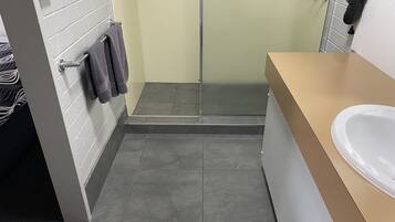 Un baño con ducha, lavamanos y un perchero para toallas.