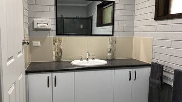 Un baño moderno con un lavabo blanco, encimera oscura y un espejo sobre el lavabo.