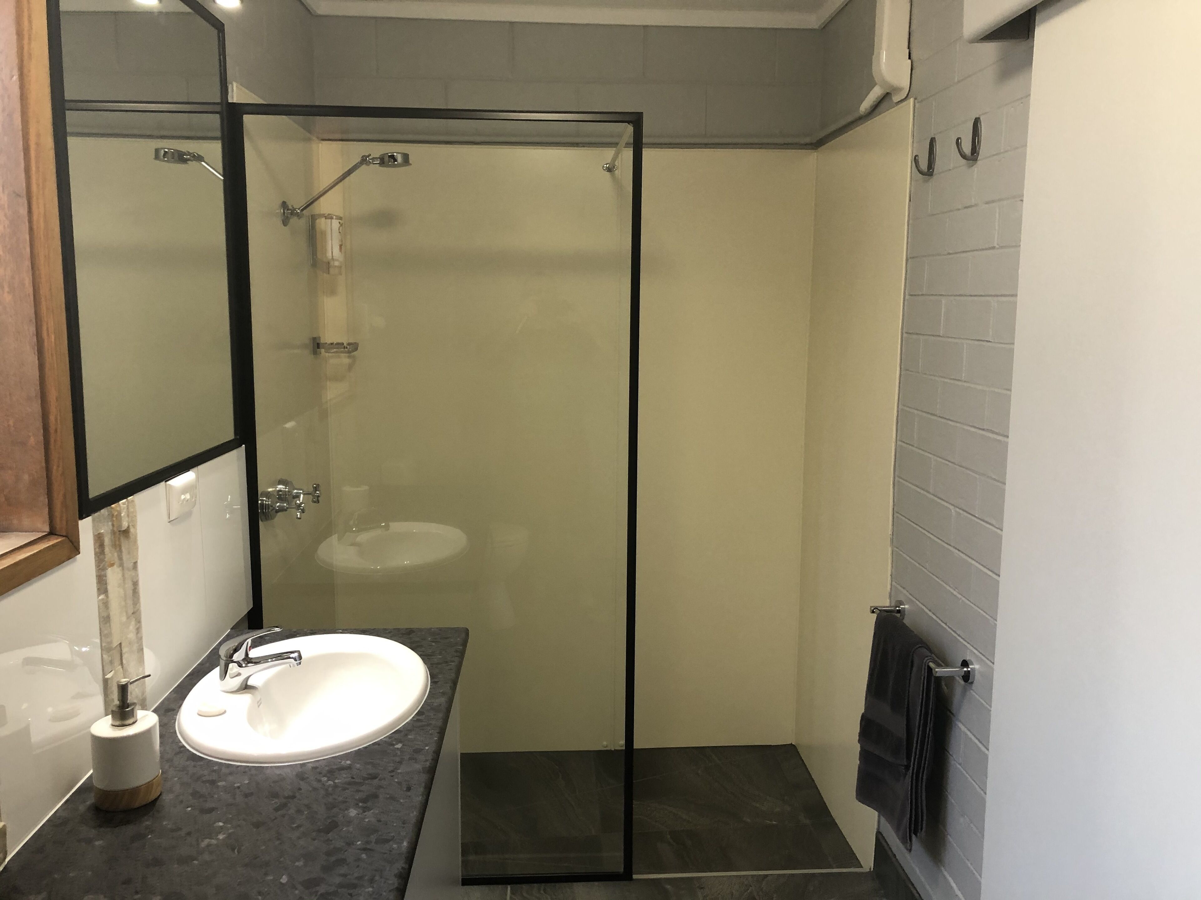 A modern bathroom with a glass-enclosed shower, a white sink, and a towel rack.
