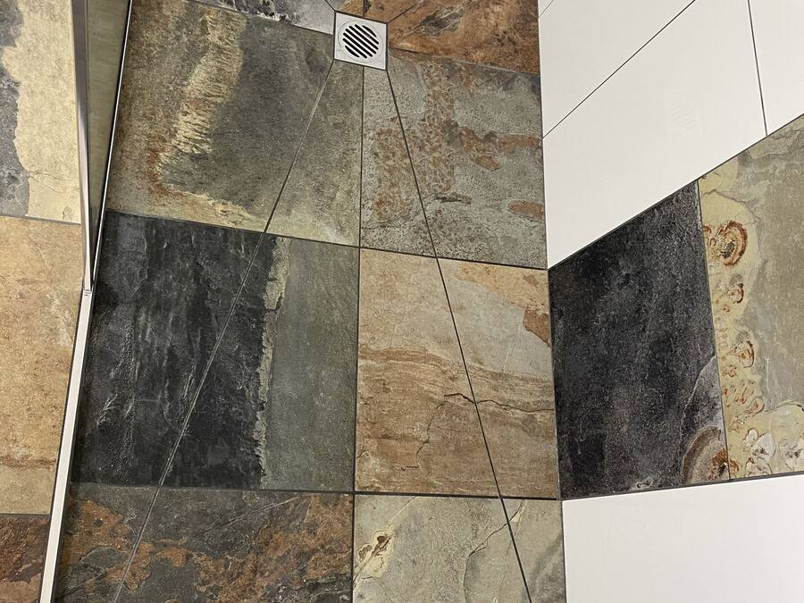 A modern bathroom with a variety of stone tiles in different shades and patterns.
