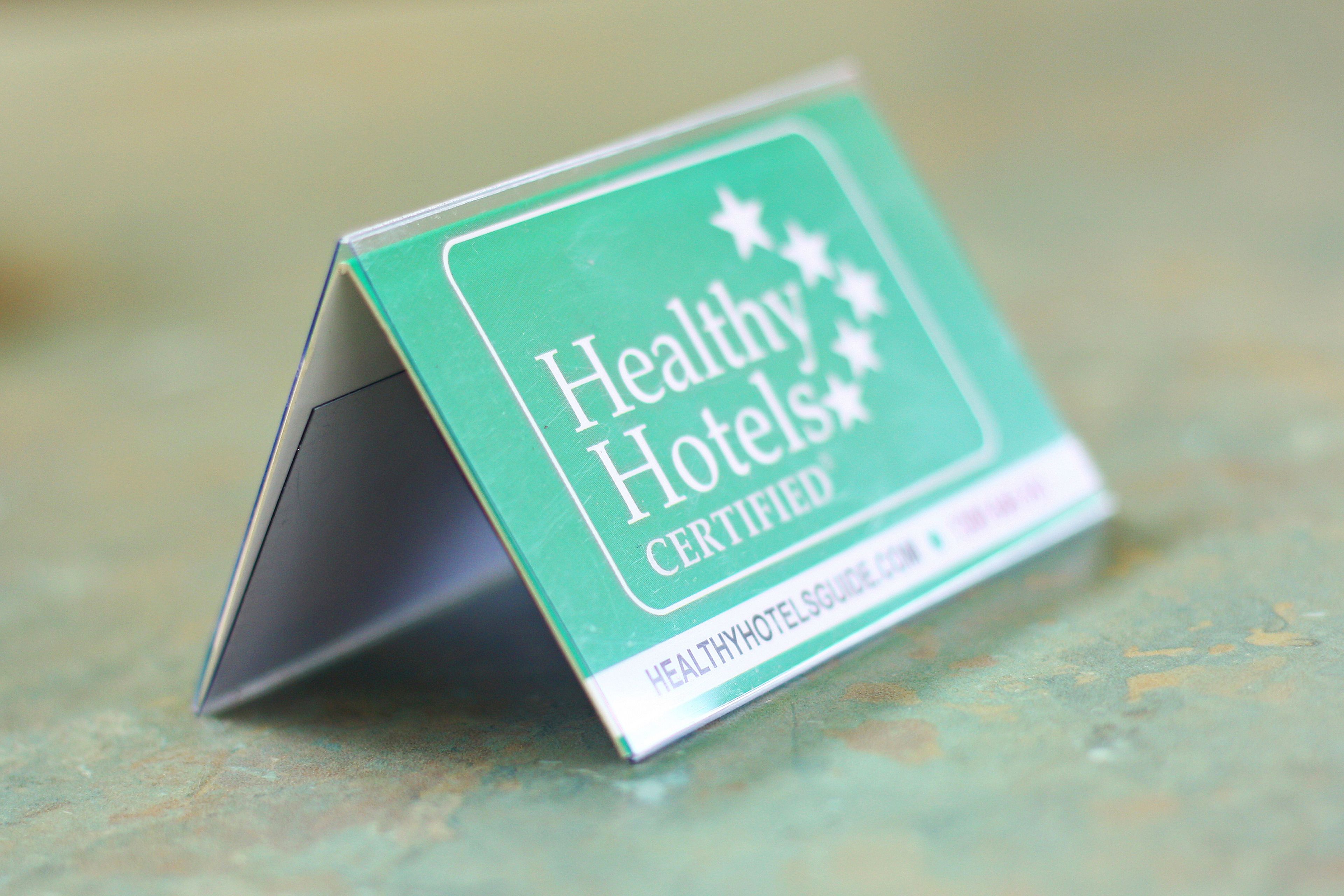 A green sign with the text "Healthy Hotels Certified" and a website URL.