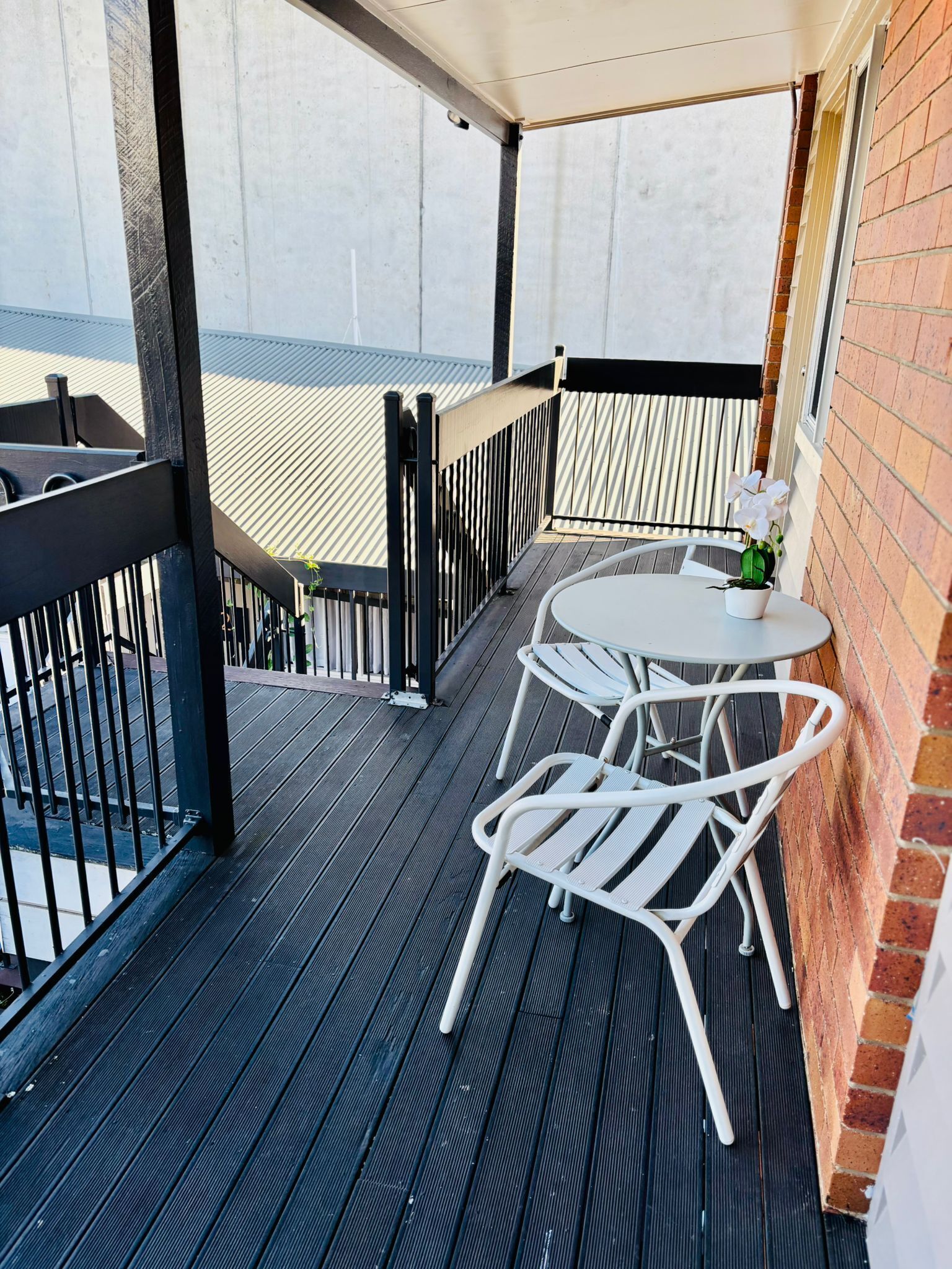 A balcony with a table and chairs, a potted plant, and a view of the building's exterior.