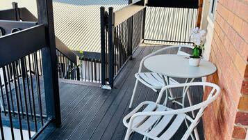 A balcony with a table and chairs, a potted plant, and a view of the building's exterior.
