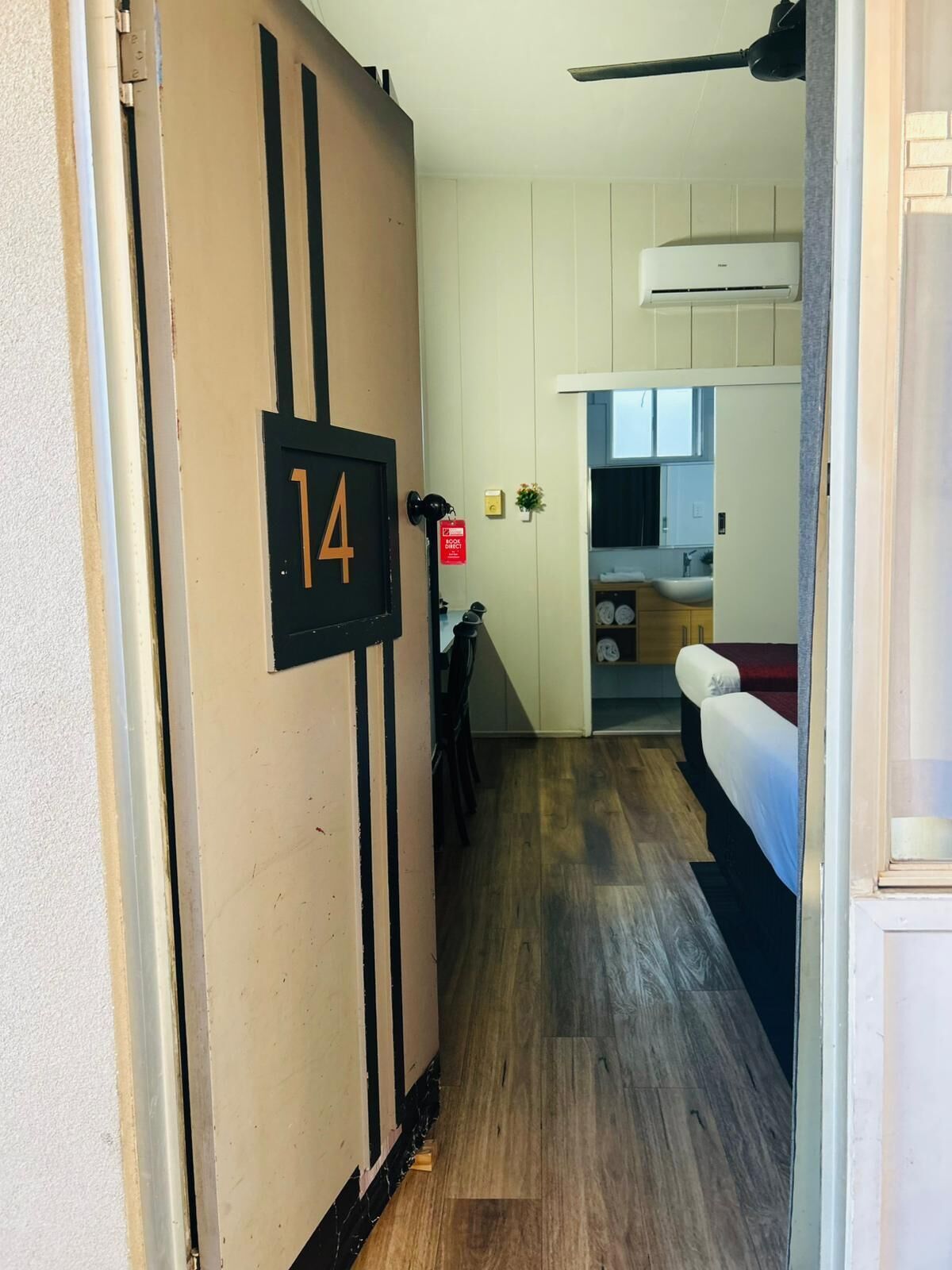 Ein Flur, der zu einem Schlafzimmer mit der Nummer 14, einem Feuerlöscher und einer Küchenzeile führt.