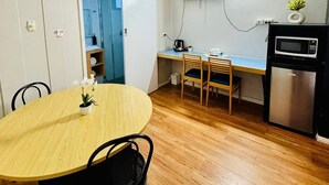 A compact kitchen with a dining area, a TV mounted on the wall, and a small refrigerator. - Downs Motel (South Toowoomba)