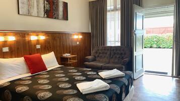 A hotel room with a large bed, a seating area, and a view of the outdoors.