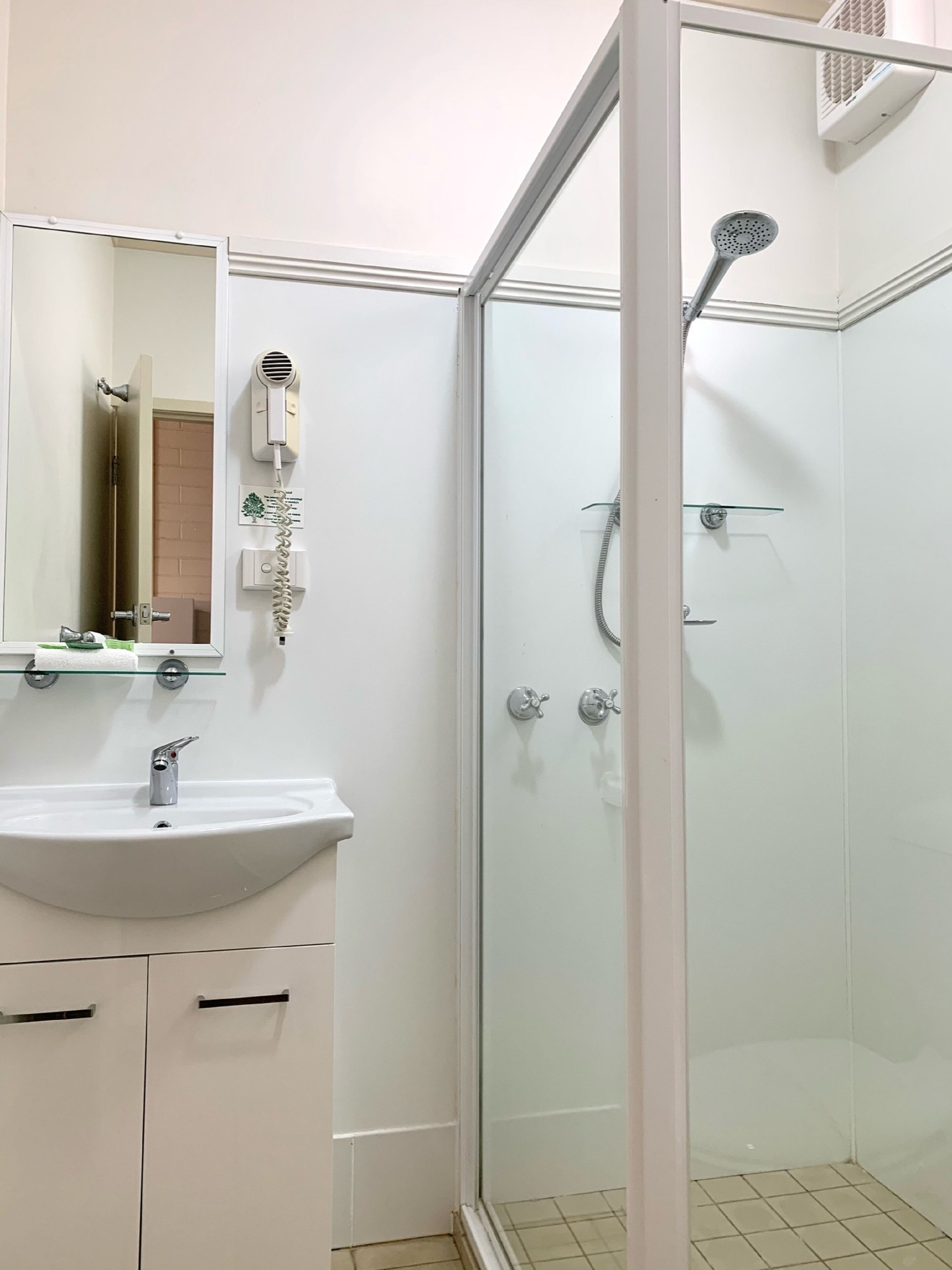 Une salle de bain moderne avec une douche à parois de verre, un lavabo blanc et un miroir au-dessus du lavabo.