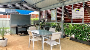 Un patio al aire libre con una parrilla, asientos y un letrero que indica que el área de barbacoa cierra todos los días a las 10pm.