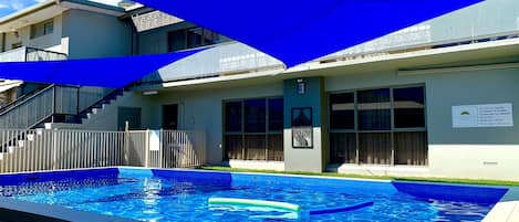 Una piscina al aire libre, sombrillas, sillones reclinables de piscina