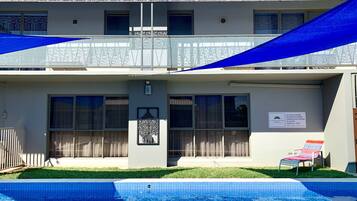 Um hotel com piscina, estrutura em dois andares e placa indicando proibição de estacionamento para veículos com vidro.
