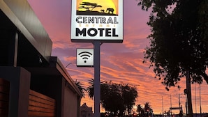 Señal del motel Central Safari con fondo de atardecer.