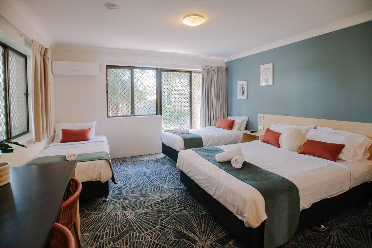 Habitación de hotel con dos camas, un escritorio y una silla.