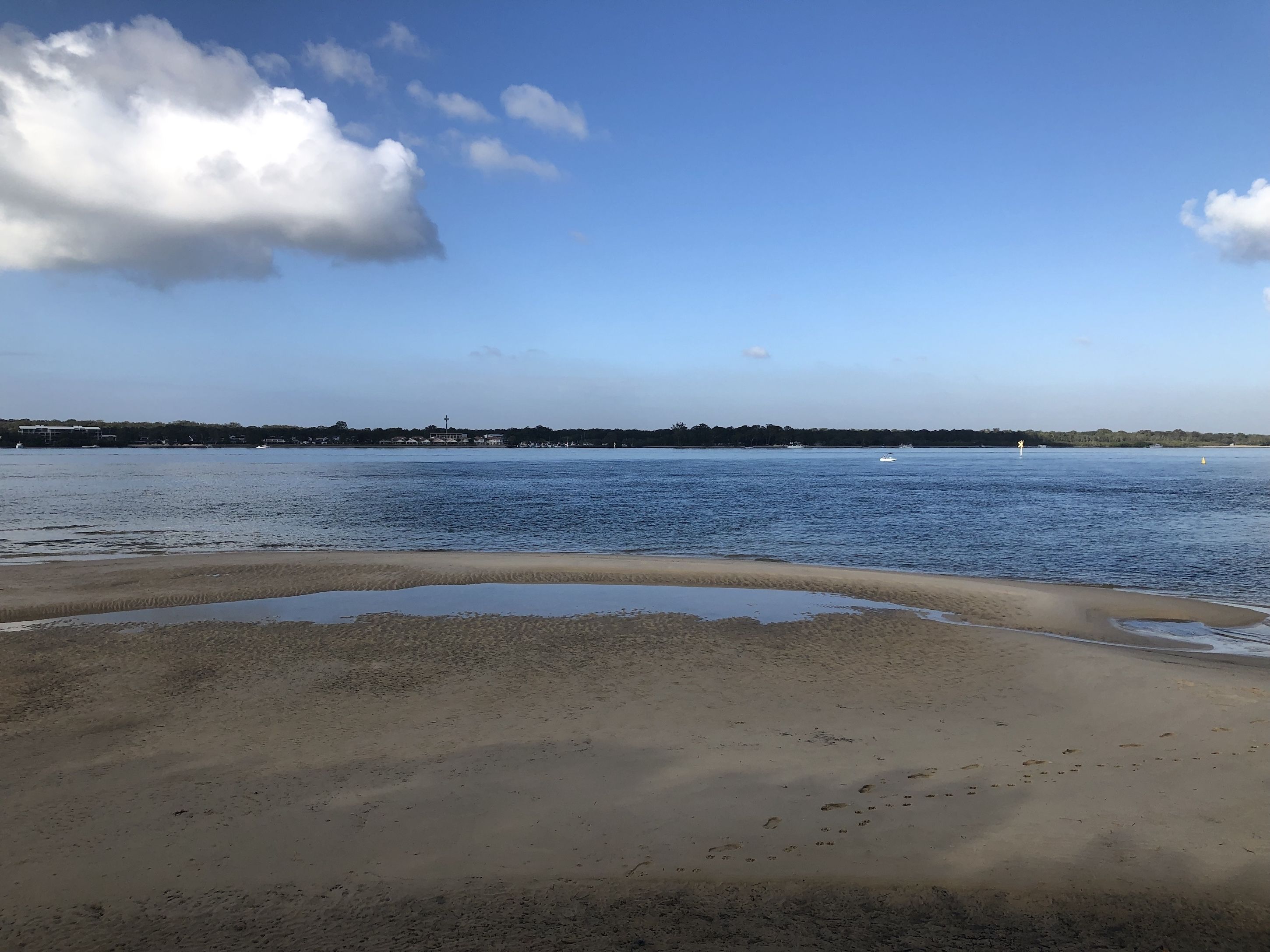 Een strand met een zandige kustlijn en kalm water.