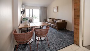 Una sala de estar moderna con comedor, que incluye un sofá de cuero marrón, una mesa de comedor de madera y sillas de mimbre.