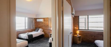 A hotel room with two beds, a TV mounted on the wall, and a window with a view.