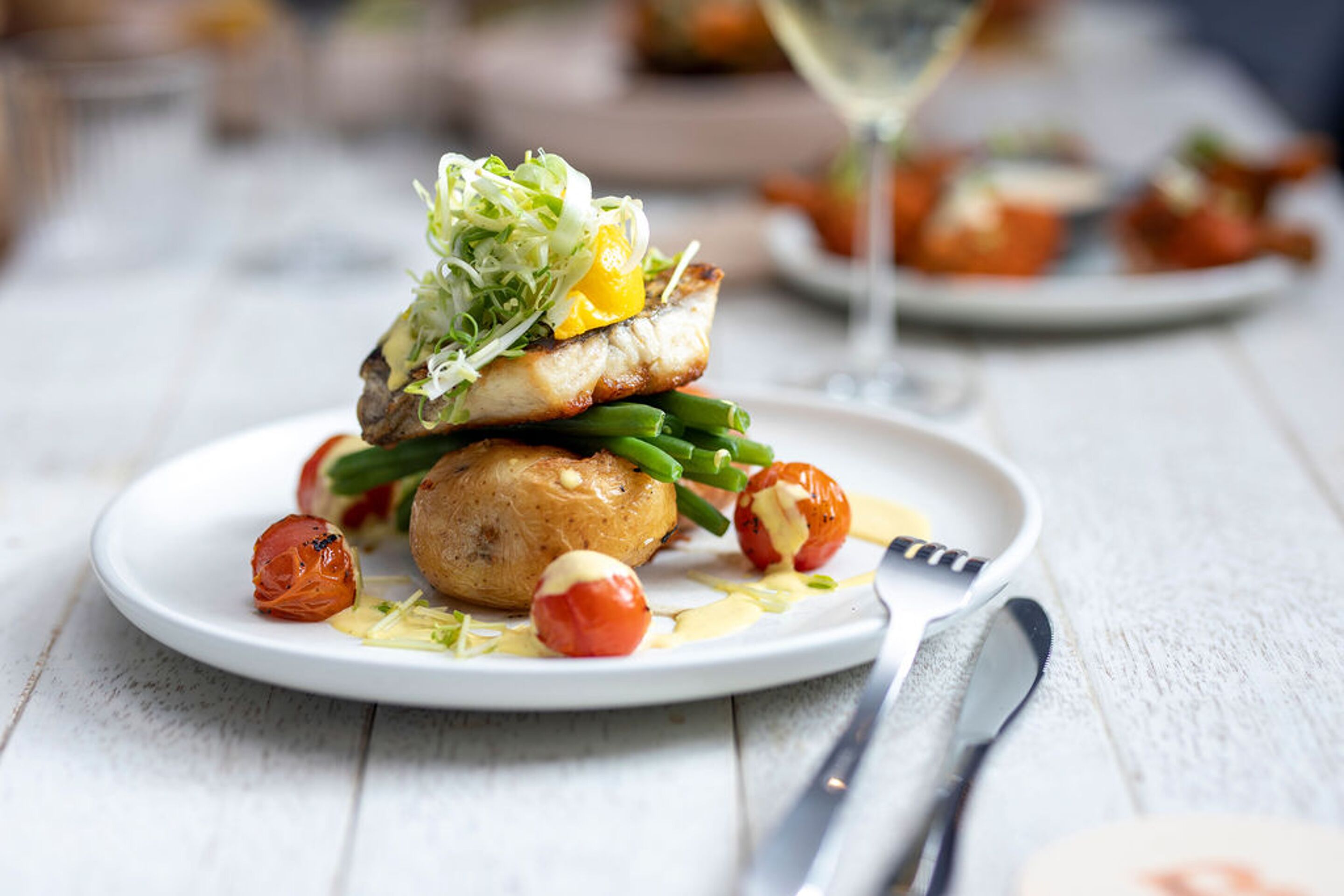 A plate of food with a variety of vegetables and a glass of white wine.