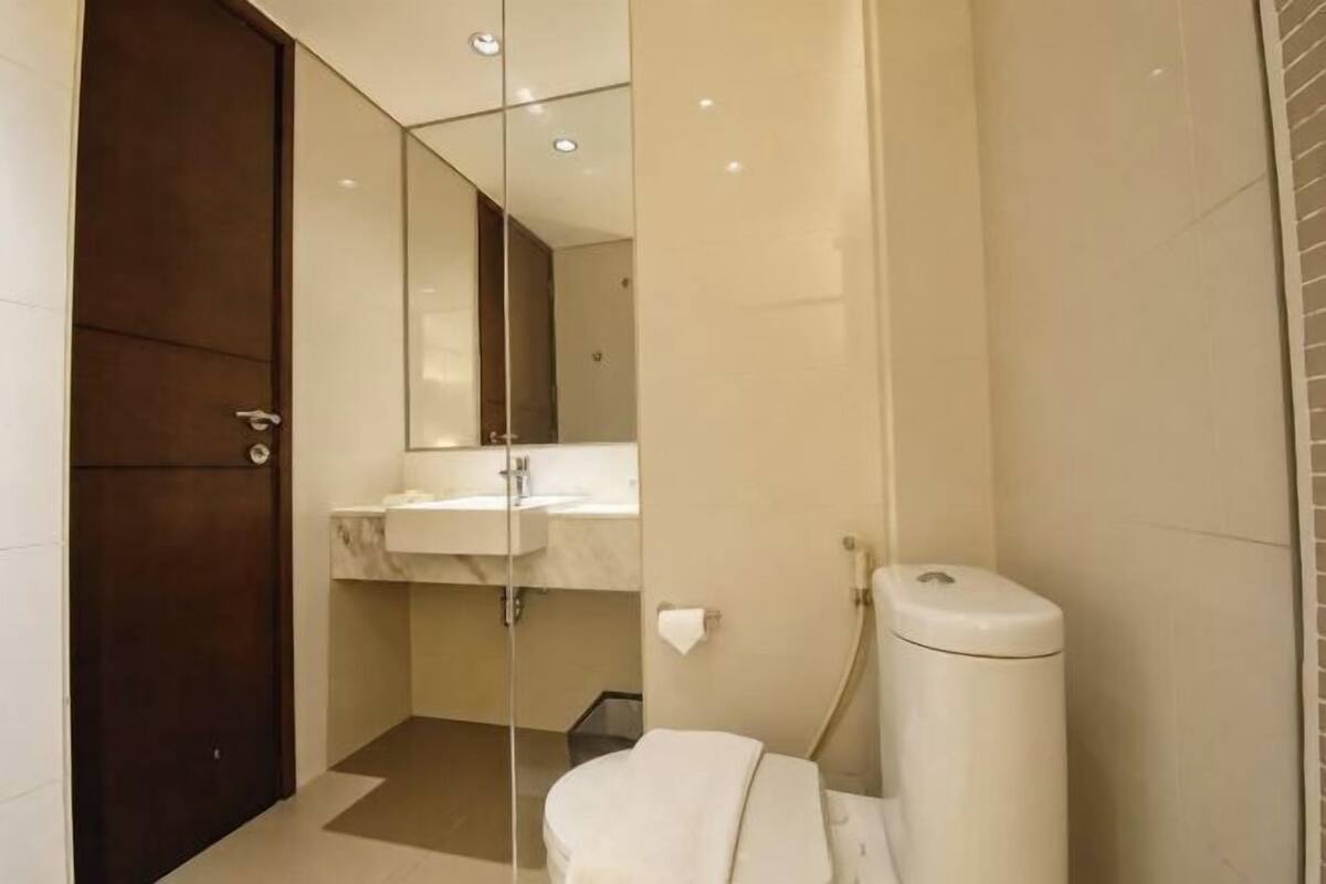 A bathroom with a toilet, sink, and mirror.