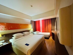A hotel room with two beds, a desk with a lamp, and a window with red curtains. - Soll Marina Hotel Serpong (South Tangerang)