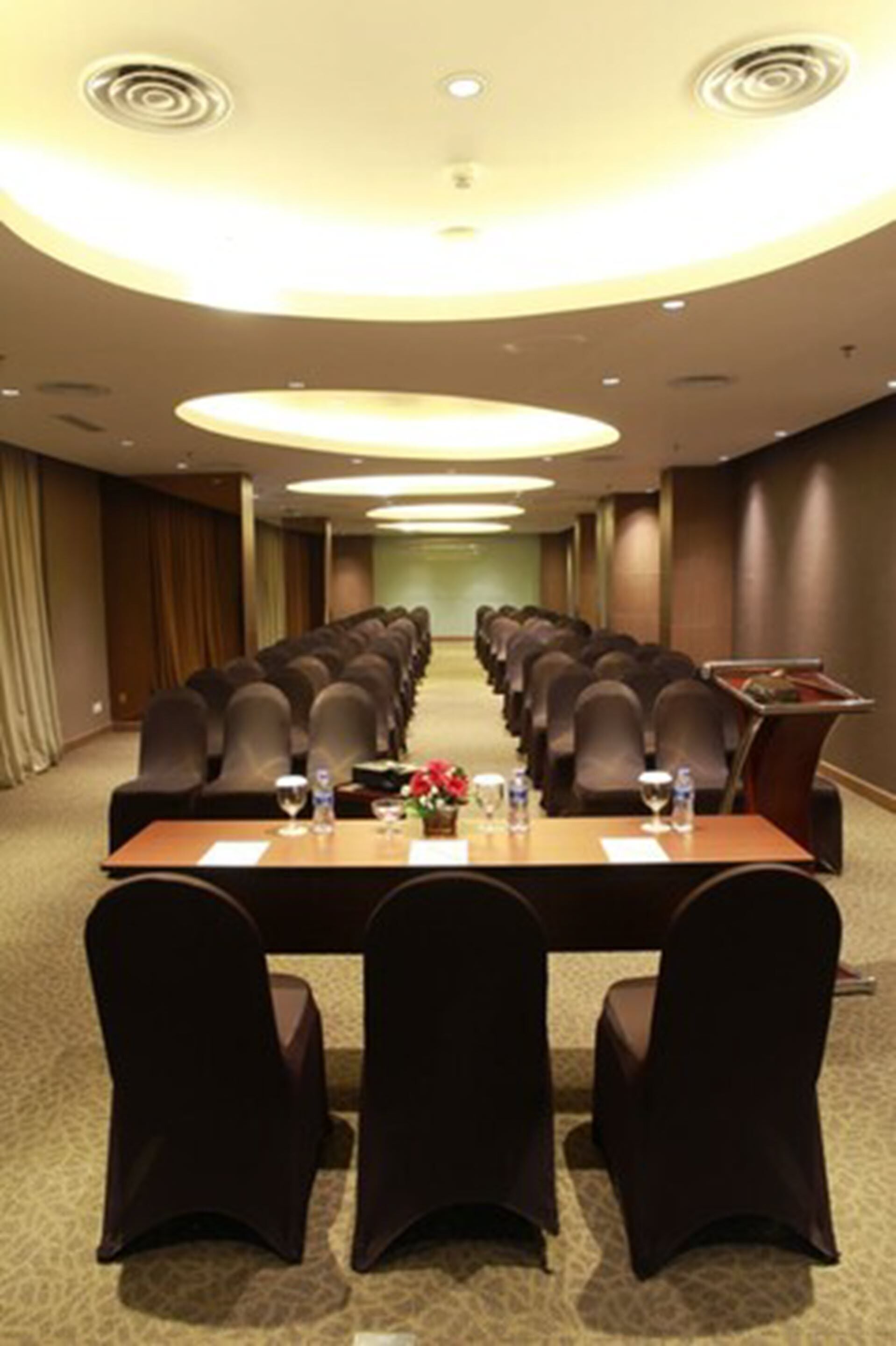 A conference room with a long table, chairs, and a podium.