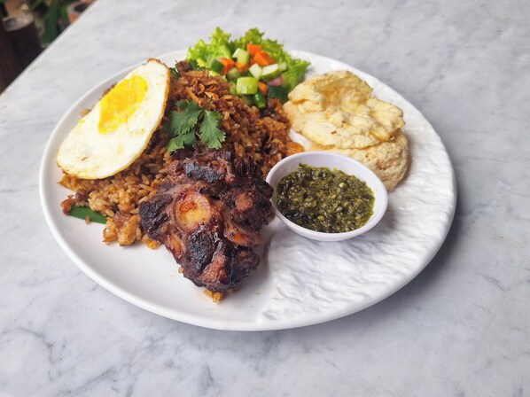 Un plato de comida con arroz, carne, un huevo cocido y una ensalada.