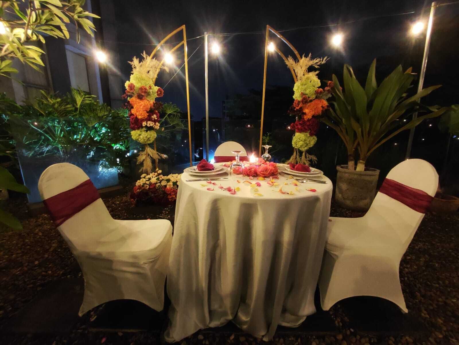 An outdoor dining setup with a round table, two chairs, and floral decorations.