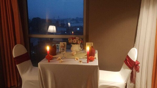 A table set for two with candles, a vase of flowers, and a lamp.