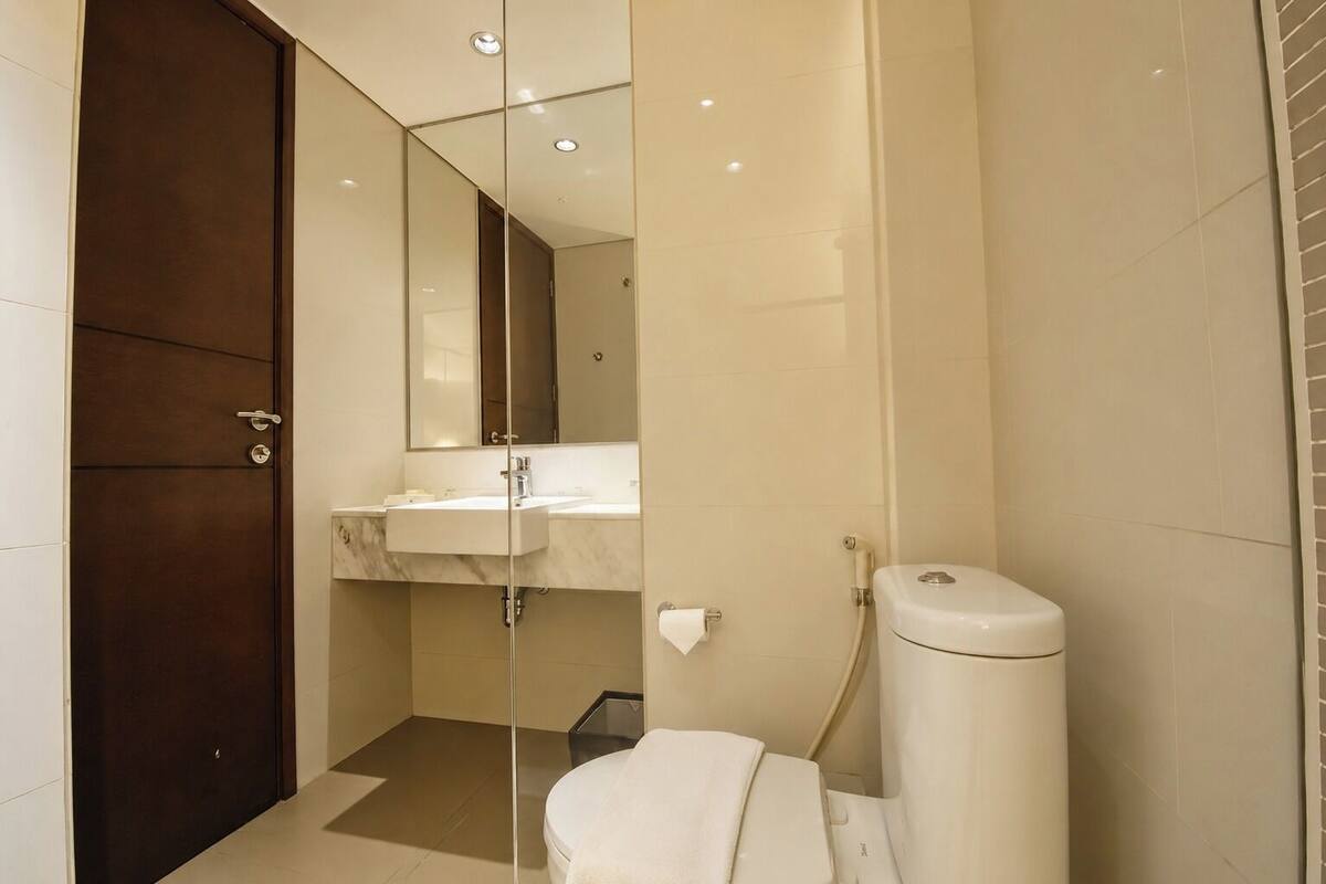 A bathroom with a toilet, sink, and mirror.