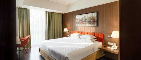 Ein Hotelzimmer mit einem großen Bett, einem Schreibtisch mit Telefon und einem Sessel.